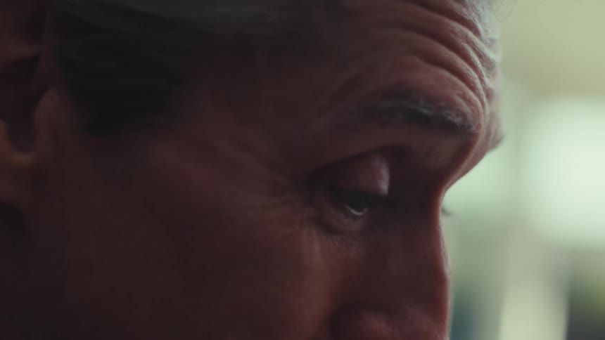 A man smiles and speaks while sitting indoors