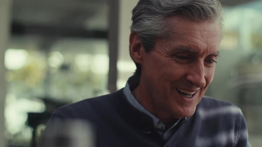 Portrait of a man sitting outside his house talking happily