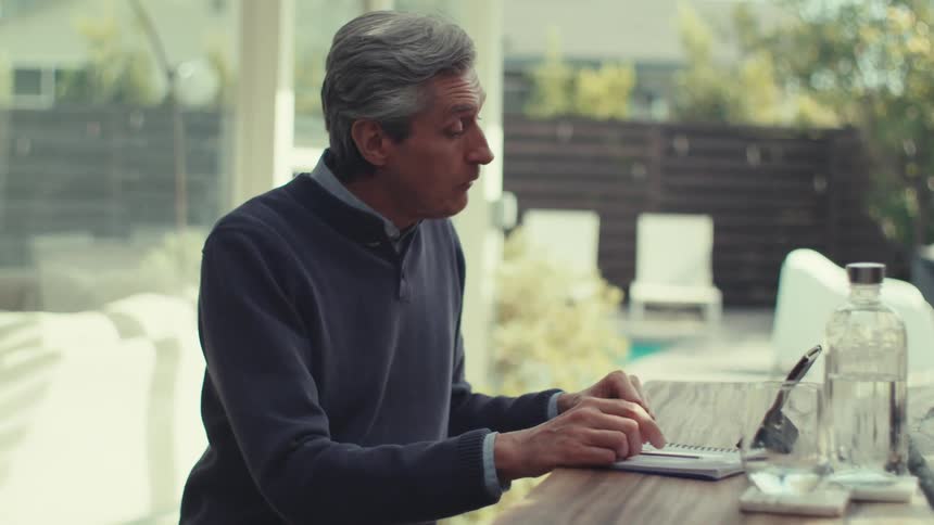 Man sitting and talking in front of a tablet on a table with a bottle of water