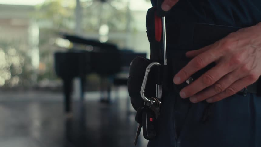 A man puts a screwdriver in his tool belt