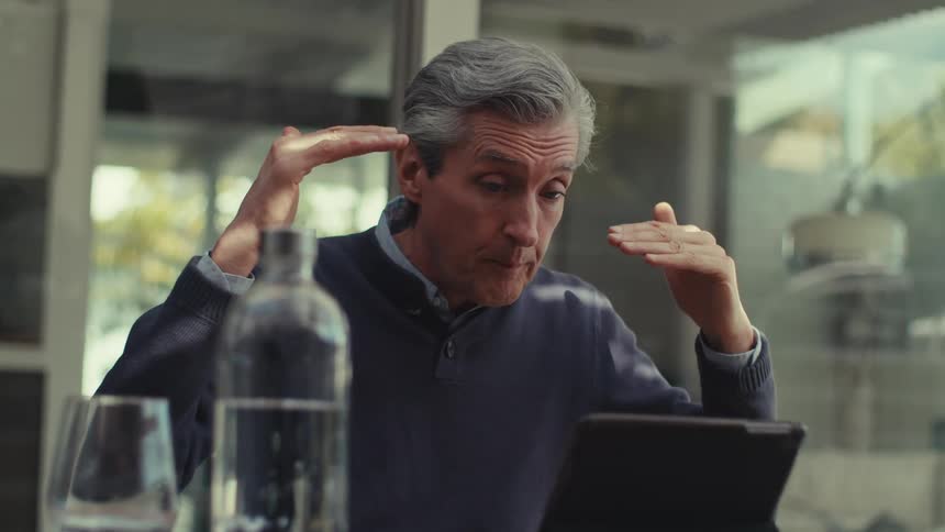 A man is seated and talking on his tablet