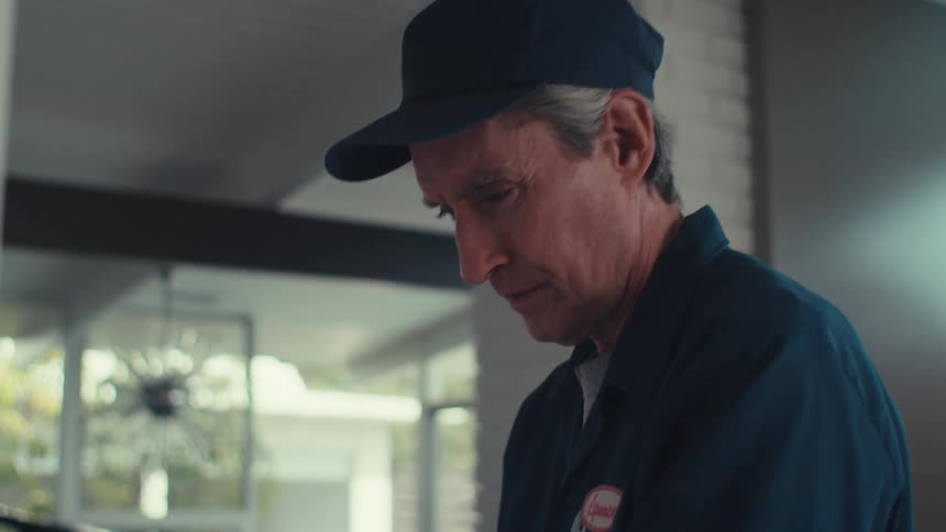 Man in cap wearing blue clothing working on a wall of a house