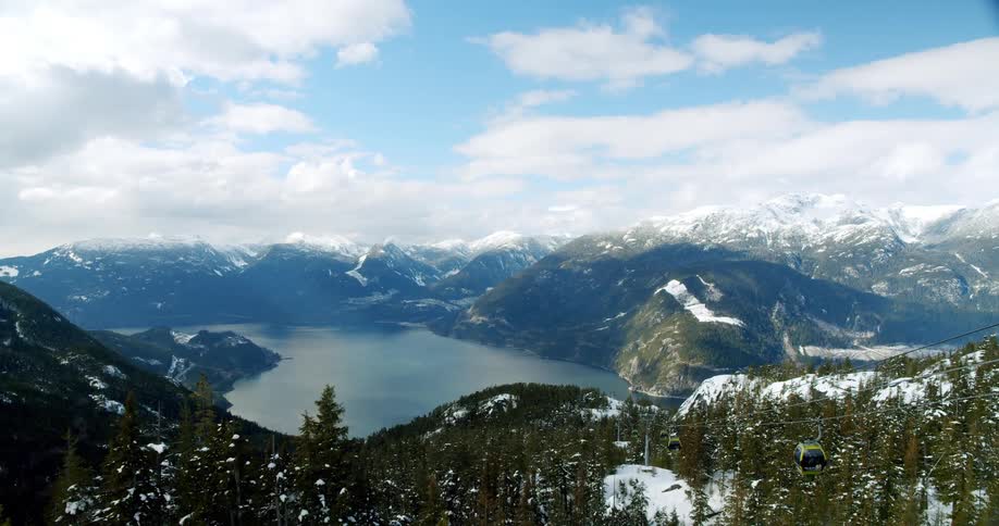 Aerial shot of a cable car in a snowy mountain landscape with a lake in the background