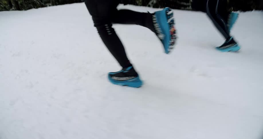 Legs of two people running in the snow
