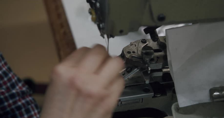 A person puts stitches on clothes with a sewing machine