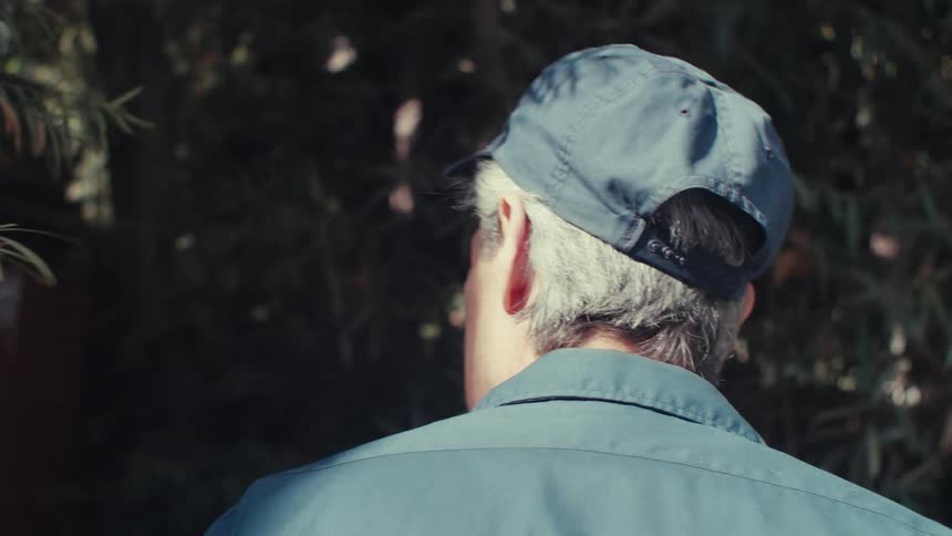 A handyman walks around the back of a house searching for utilities
