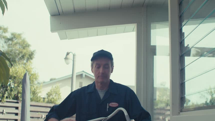 A man sets up a foot ladder by the side of the home