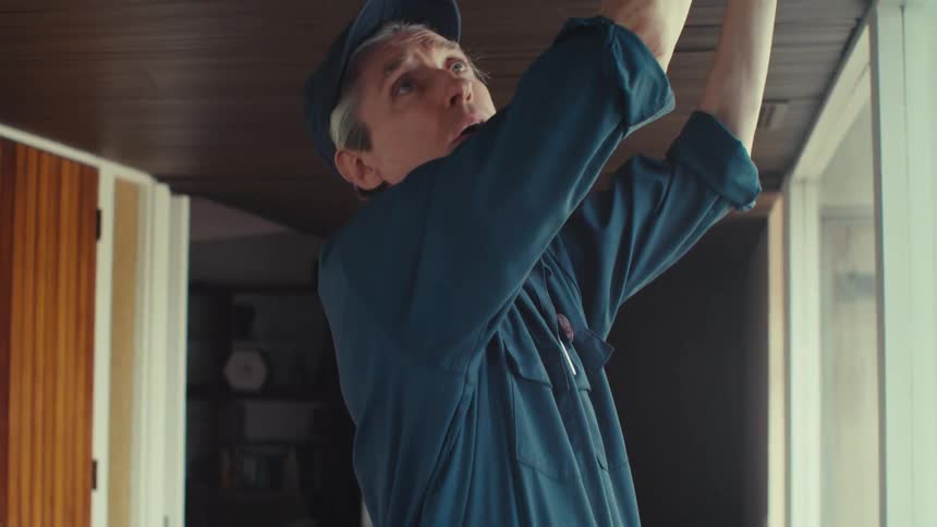 A handyman measures the distance to a grate on the ceiling of a modern house