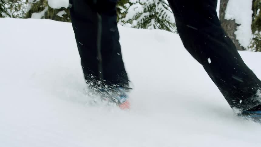 Feet of a person wearing blue sneakers running in the snow