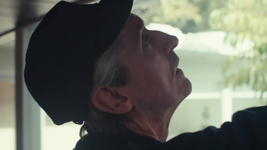 Male trades person takes measurements of the ceiling near a window