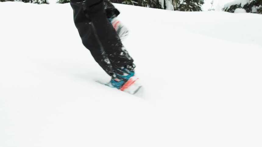 Person runs through the snow near conifers while it snows