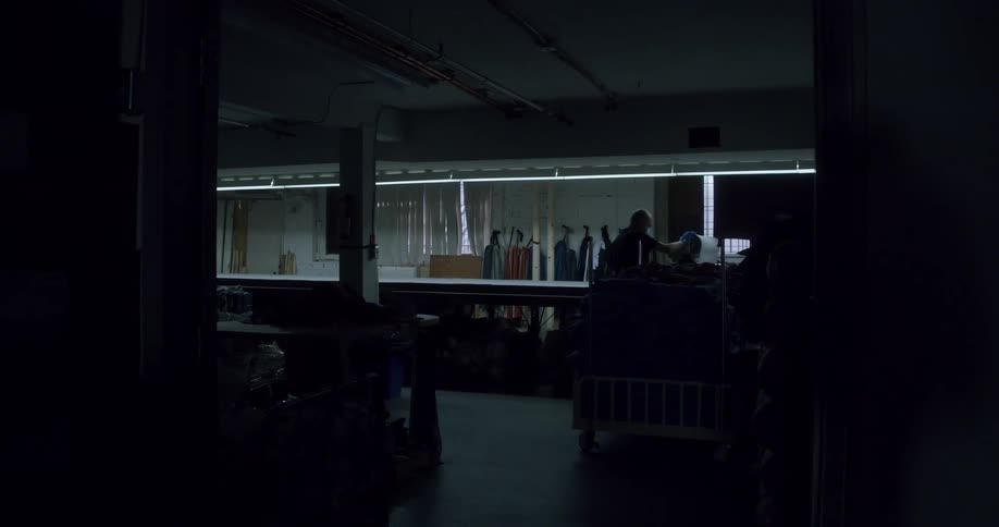 Silhouette of a person carrying a machine inside a factory