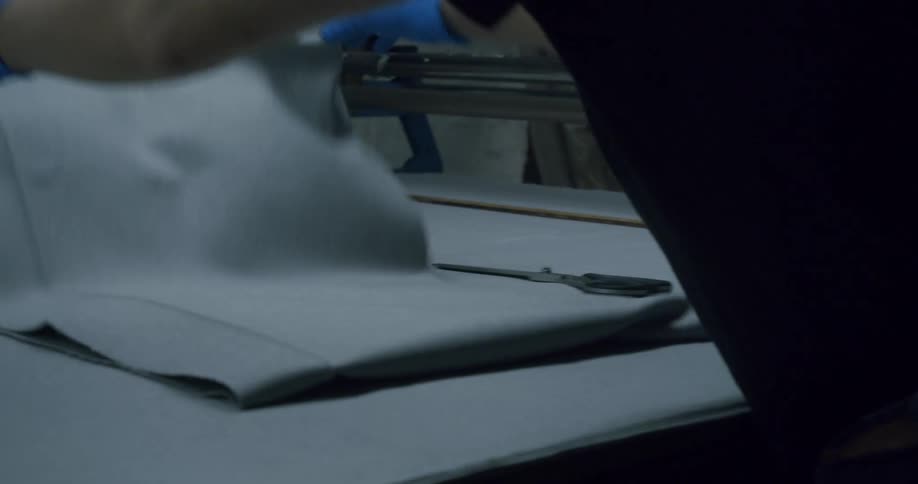 Person cuts and folds fabric while in a workshop