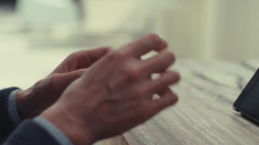Hands of a person gesturing towards a small tablet