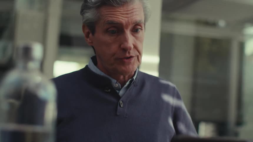 A man is very animated while gesturing as he talks in front of a tablet computer