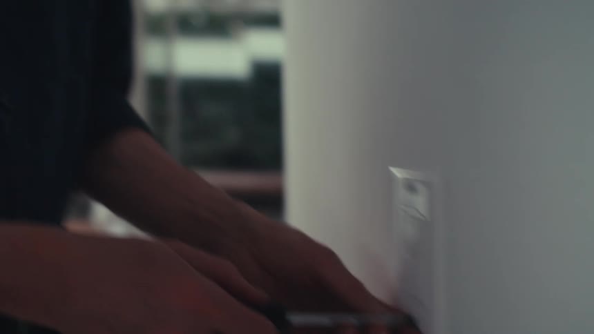 A person use a screwdriver to tighten a screw on a wallmounted light switch