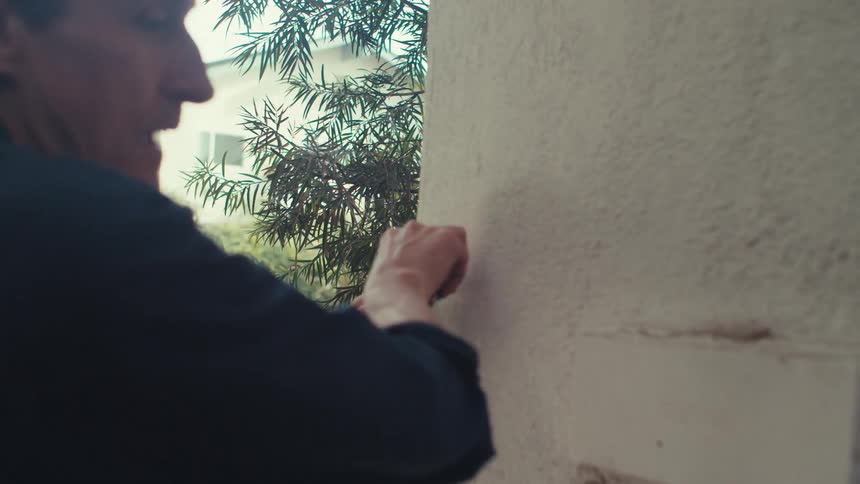 Man with a tape measure measuring a wall in an outdoor area