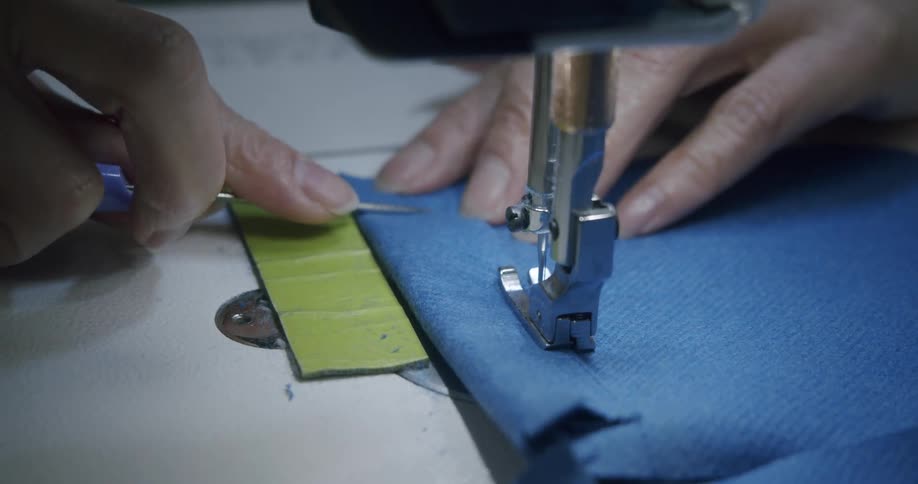 A seamstress sews a piece of blue fabric with a sewing machine