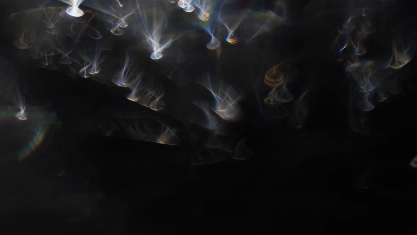 A surface of a shiny object reflecting some lights in a smoky shape