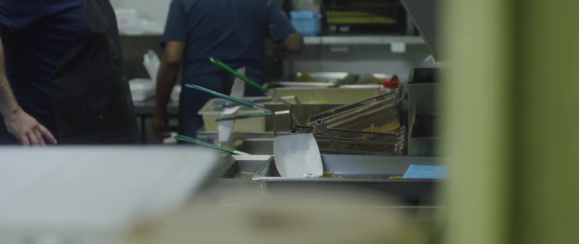 People working inside a restaurant kitchen with fried food