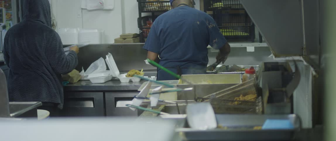 People are cooking food and placing them in cartons