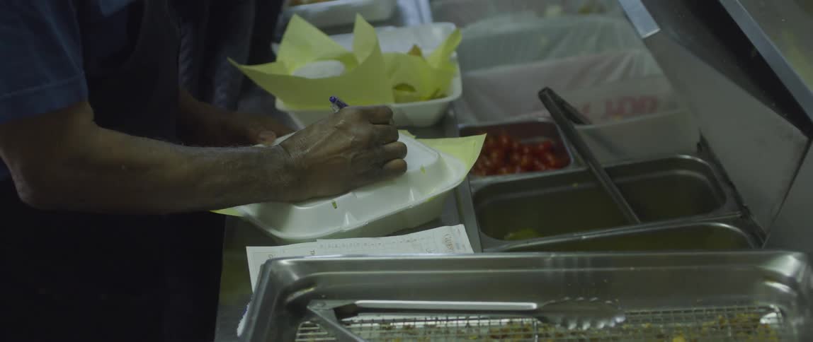 A person writing on a takeaway pack in a restaurant