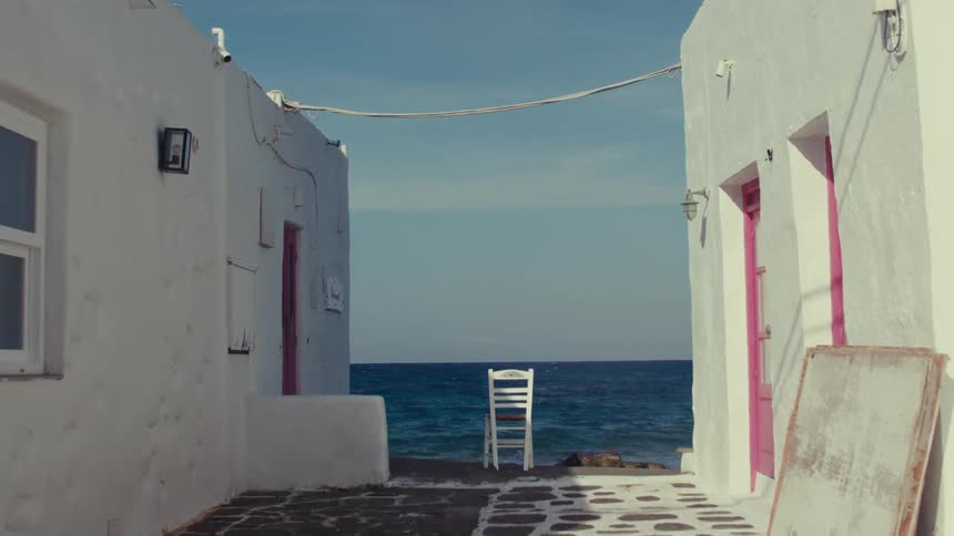 A chair facing the ocean is centered between two housing units