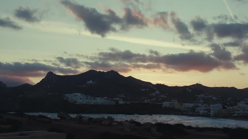 Shoreline of a coastal city next to a mountain during dusk or dawn