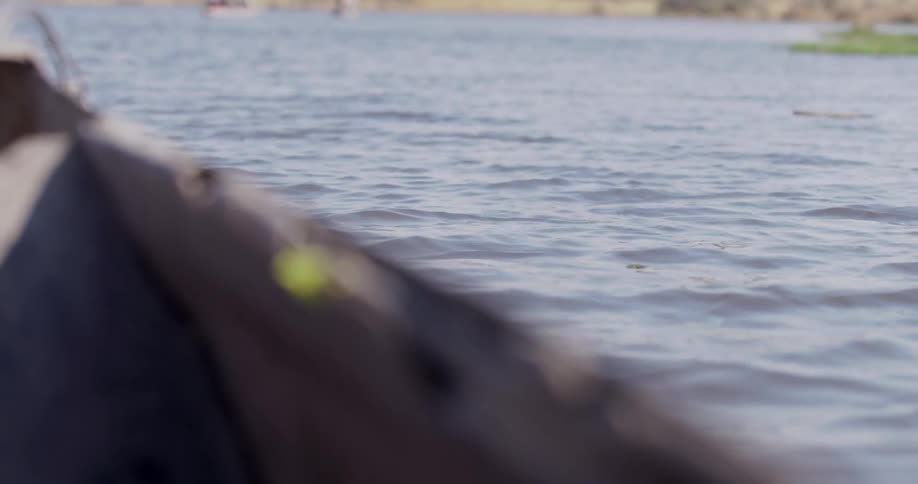 Wooden boat floats through the water near the shore during the daytime