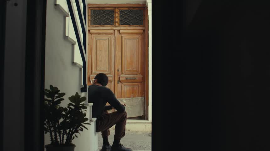 A person is sitting on a step in front of a large ornate wooden door