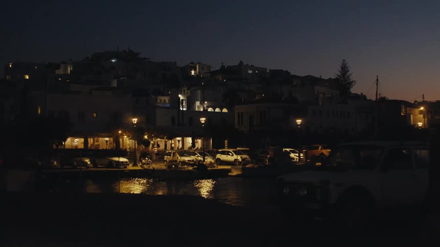 Series of white buildings on a hill next to the shoreline during dusk time