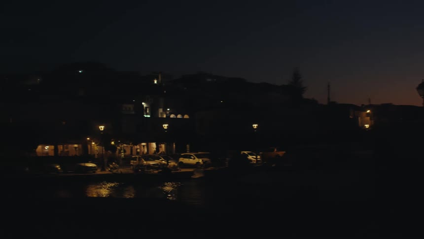 The sun dips below the horizon casting a warm orange glow over a harbor silhouetted against the darkening sky
