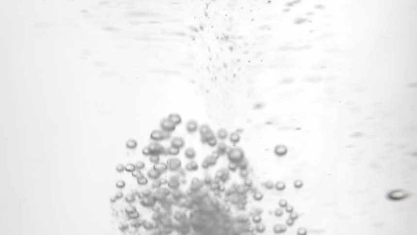 A tablet of antacid dissolving in a glass of water