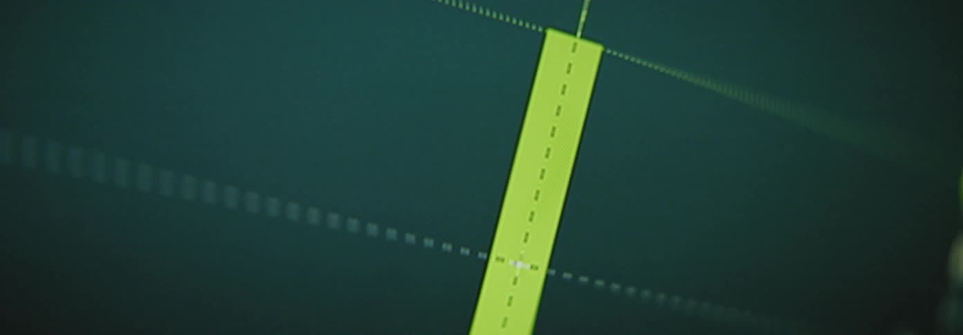 A large monitor flashes red and yellow bars that look like a chart