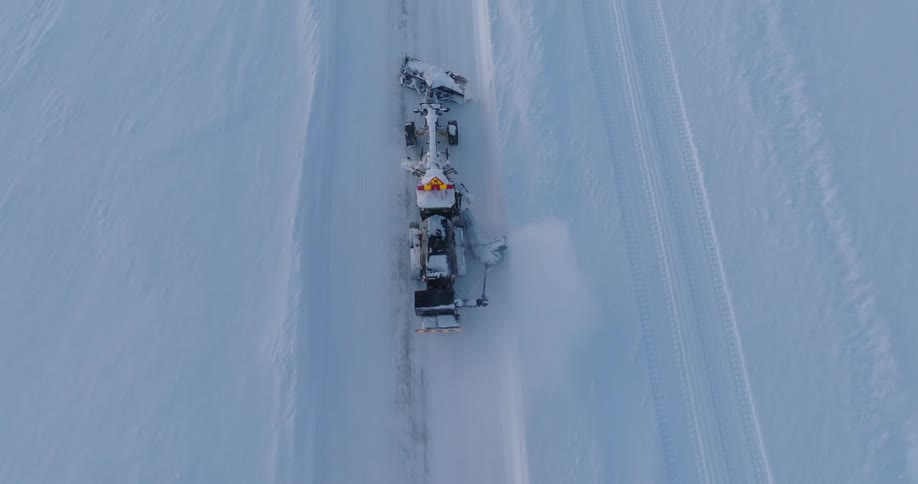 An aerial view shows a snow plow clearing a snow covered road