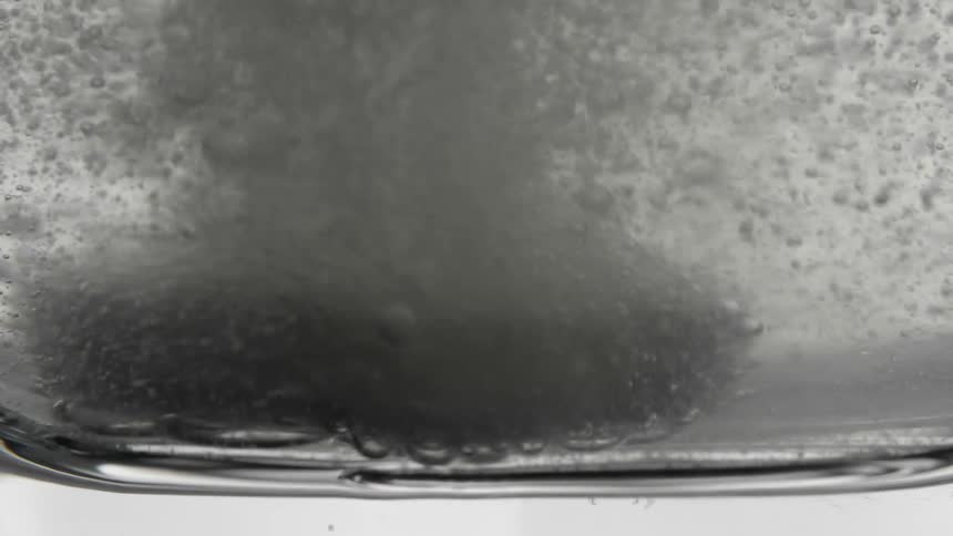 Medicine capsule falling into a glass of water and dissolving