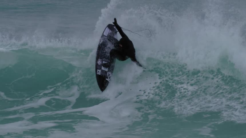 A person on a surfboard rides a gigantic wave in the ocean