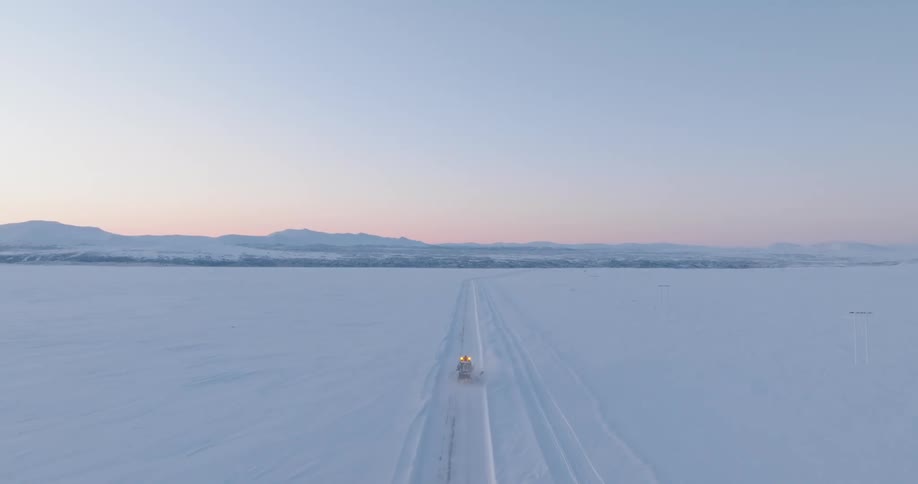 Motor vehicle drives along highway passing through a snow covered rural countryside