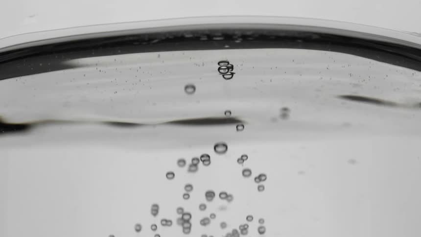 A clear liquid begins to move and many small bubbles begin to emerge