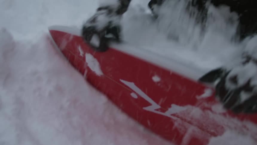 Man digging a surfboard out of the snow