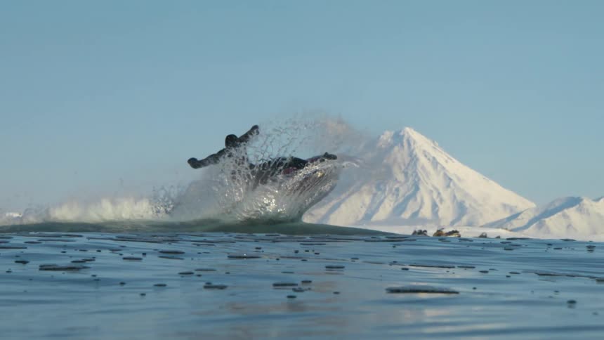 A man crashes as he surfs in the icy water