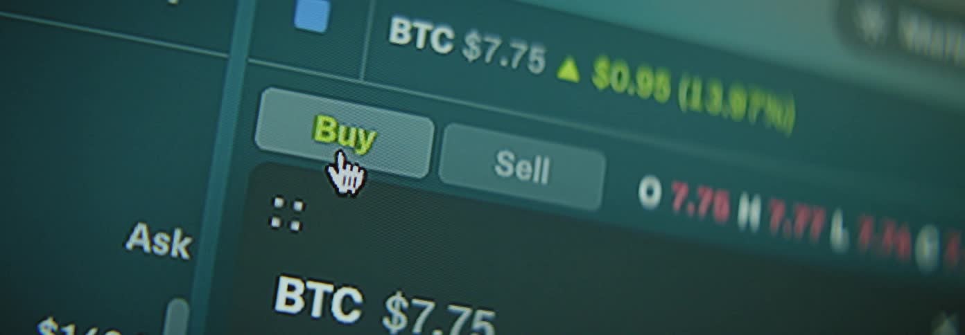 A closeup view of a cryptocurrency trading platform showing a bitcoin price and buy and sell buttons