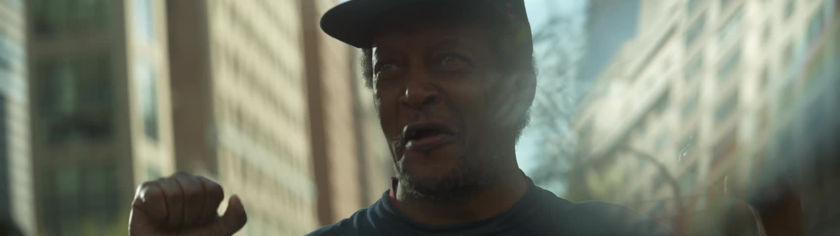 A man starts to open his mouth while standing next to a building