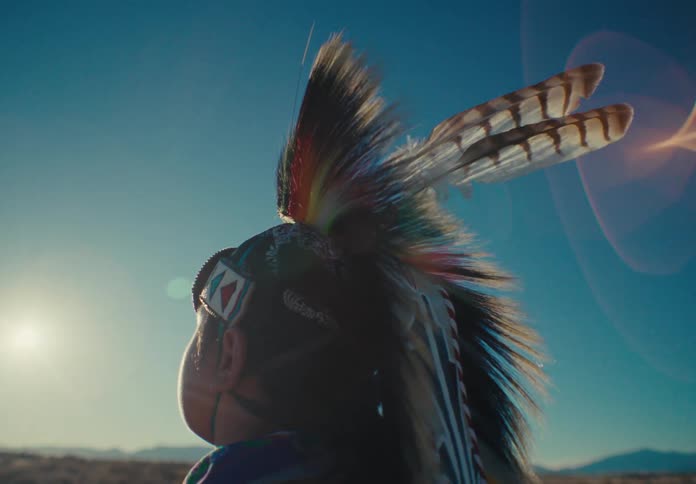 A closeup of a headdress with feathers glistening under the bright sun