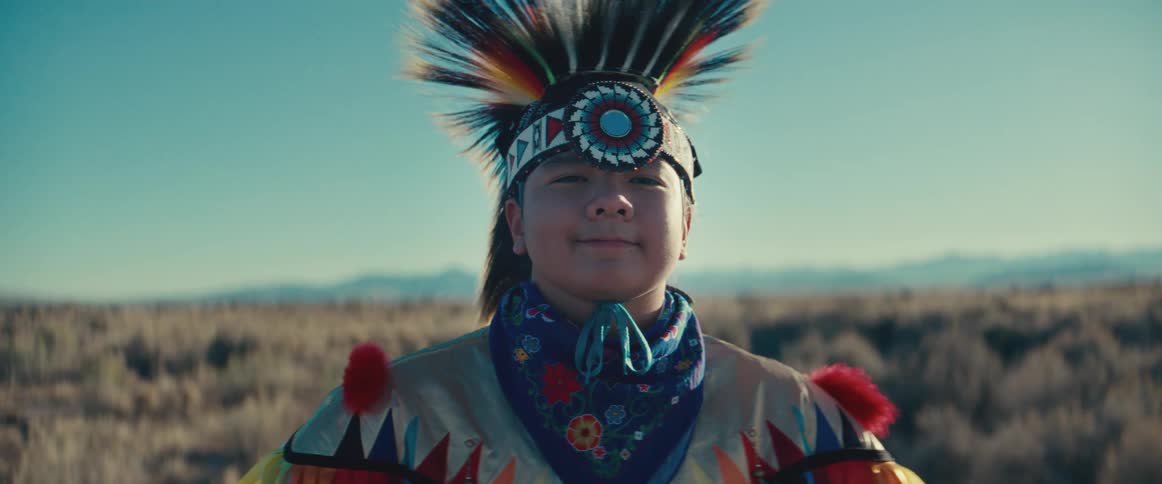 Portrait of a young native american person wearing a cap and while standing in a field with undergrowth