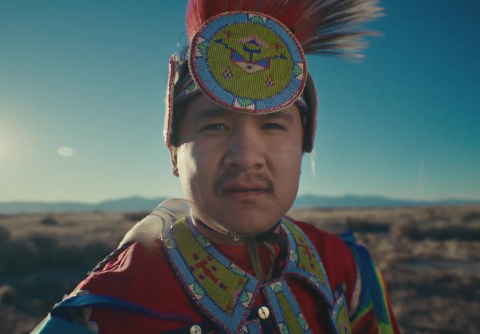 Portrait of a man in a colorful outfit and a feathered hat in a field