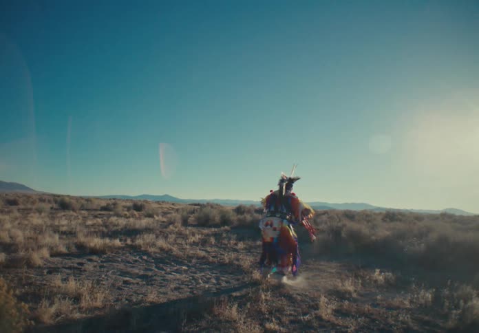 Native american tribesman dancing in a field with mountains in the background