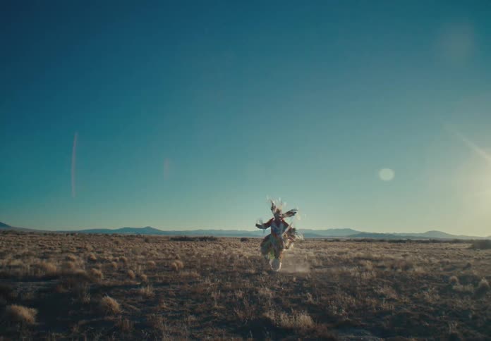Person dancing in a field in traditional native american costume