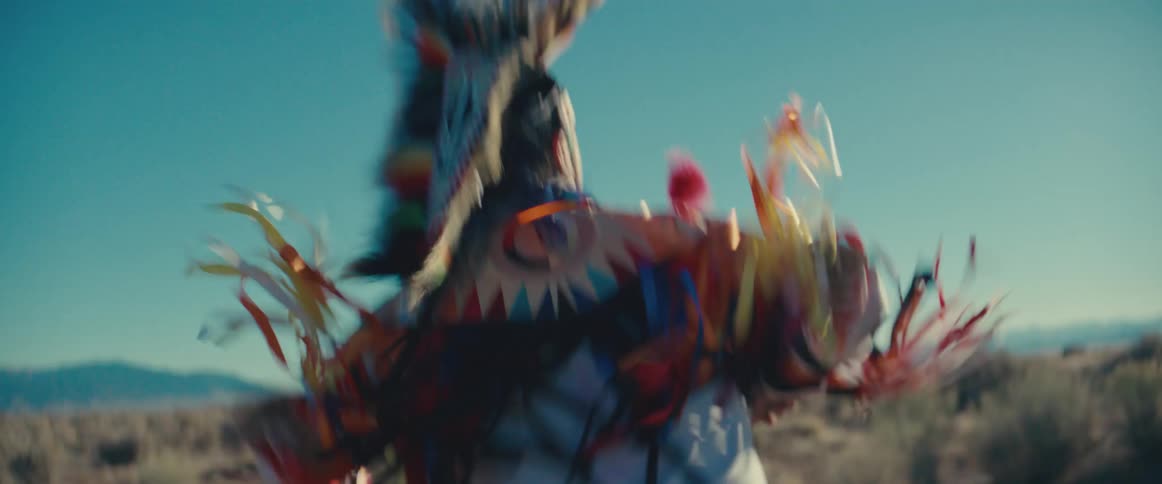 Child in traditional native american dress dancing in a field in broad daylight