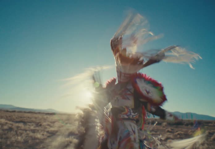 Person in a feather outfit dancing in a field